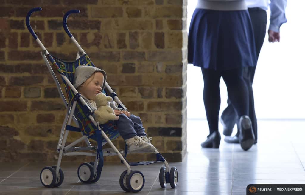 Visitors pass a sculpture entitled 'Baby in Stroller by the late U.S. artist Duane Hanson is exhibited at the Serpentine Sackler Gallery in London, June 1, 2015. Hanson's lifelike sculptures portraying working-class Americans and overlooked members of society are being brought together in the largest show of his work in Britain since 1997. REUTERS/Toby Melville